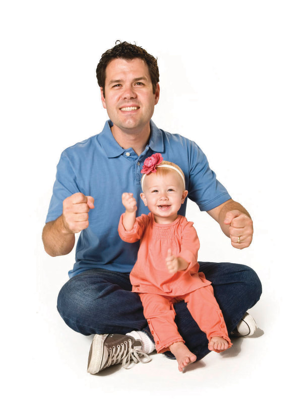 photo of young child doing hand signs with adult man, smiling